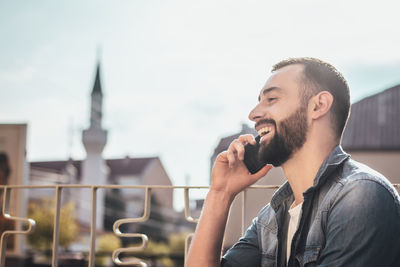 Happy man talking on mobile phone in city