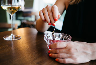 Woman eating an ice-cream, sorbet in the restaurant, close up hands, restaurant, holiday
