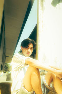 Side view of young man sitting at window