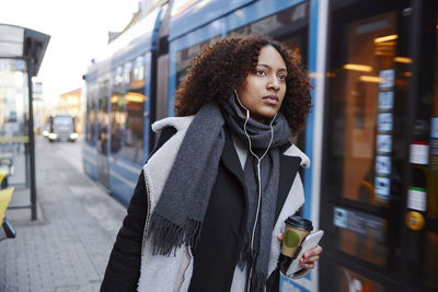 Young woman walking, tram in background