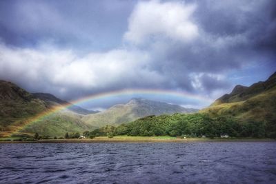 Scenic view of rainbow over lake and mountains against sky