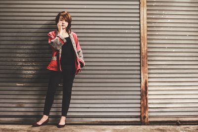 Full length of woman standing against shutter