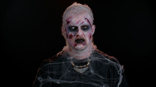 Portrait of zombie against black background