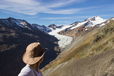Man wearing hat while standing against mountains during winter