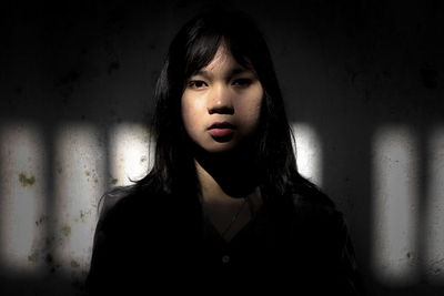 Portrait of beautiful young woman standing against wall