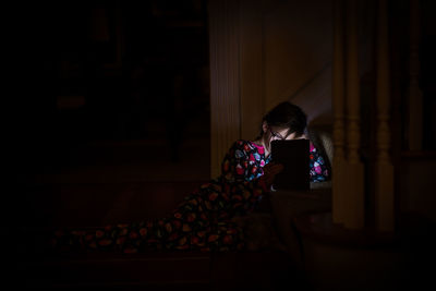 Girl using tablet computer in darkroom at home