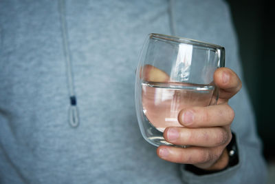 Midsection of man holding glass of water