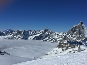 Scenic view of snowcapped mountains against clear blue sky