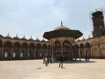 People in front of historic building against sky