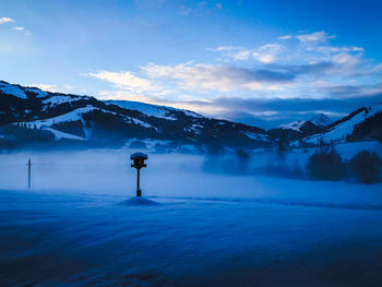 Scenic view of snow covered mountains against blue sky