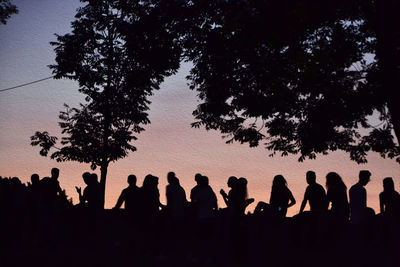 Silhouette people standing by tree against sky during sunset