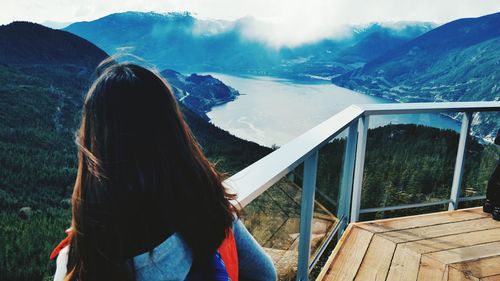 Rear view of woman standing on observation point over mountains against sky