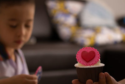 Cropped hand holding cupcake with boy in background