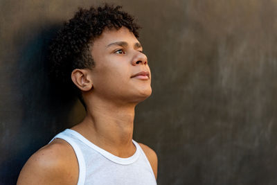 Portrait of teenage boy looking away against wall