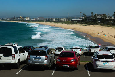 Cars on road by sea against sky in city