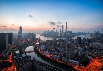 Aerial view of buildings in city against sky during sunset