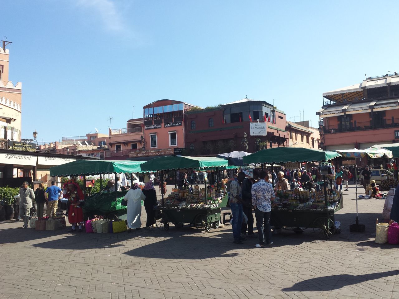 building exterior, architecture, built structure, street, city, clear sky, large group of people, sky, sunlight, person, incidental people, men, potted plant, residential building, city life, day, residential structure, outdoors, blue