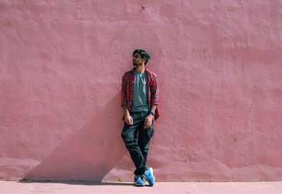 Fashionable man standing against pink wall