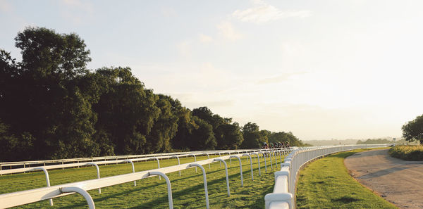 Jockey riding horses at epsom downs racecourse against sky