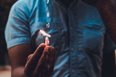 Midsection of man holding illuminated candle