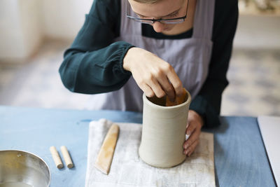 Young woman molding earthenware at table in art studio