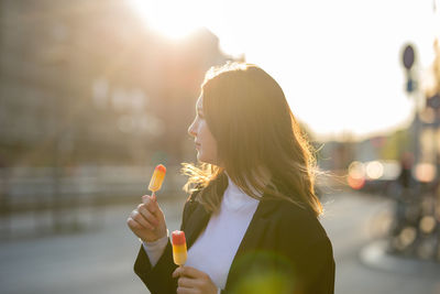 Portrait of woman holding ice cream in city