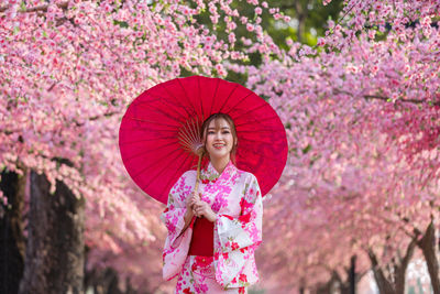 Full length of woman standing on pink cherry blossom tree