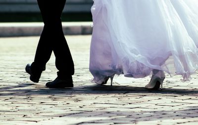 Low section of bride and groom walking on street during wedding