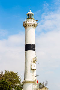 Low angle view of lighthouse by building against sky