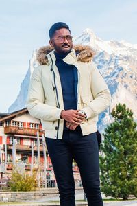 Man in warm clothing standing against snowcapped mountains