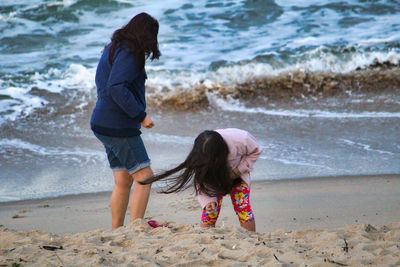 Rear view of mother and daughter on beach