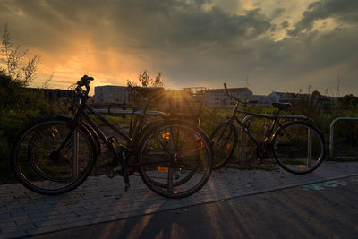 Bicycles parked on street against sky during sunset