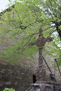 Low angle view of cross against trees