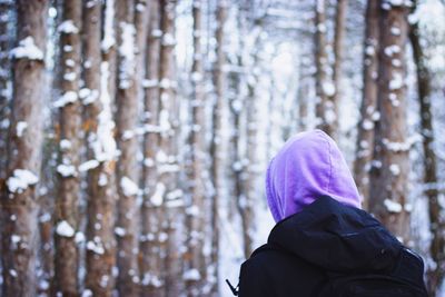 Rear view of man wearing purple hood in forest during winter