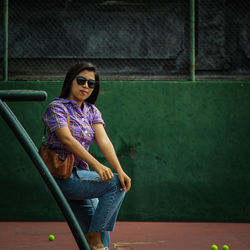 Portrait of woman sitting against wall
