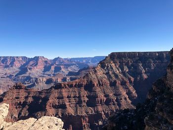 Panoramic view of rocky mountains against clear blue sky