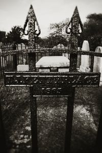 Close-up of metal fence at cemetery against sky