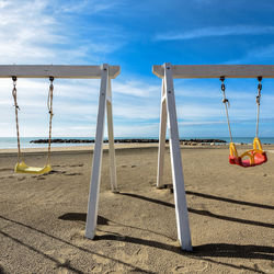 Deck chairs on beach against sky