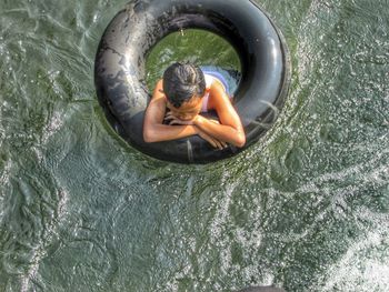 High angle view of boy swimming with inflatable raft in lake