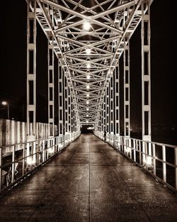 Empty footbridge along buildings at night