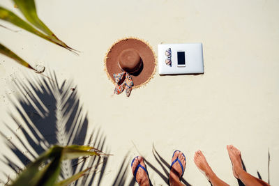 Directly above shot of sunhat with smart phone and sunglasses on beach