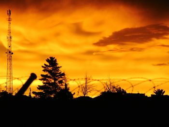 Silhouette trees against dramatic sky during sunset