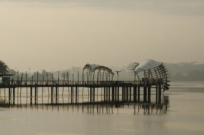 Pier on lake against sky during sunset