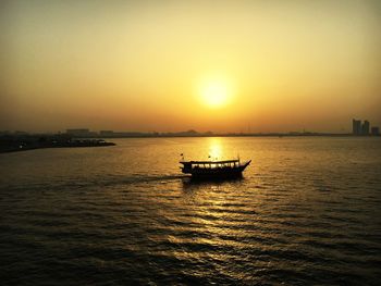 Silhouette boat sailing in sea against sky during sunset