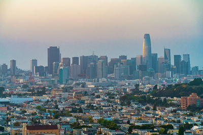 Aerial view of buildings in city against sky during sunset