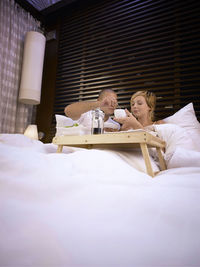 Couple sitting on bed at home