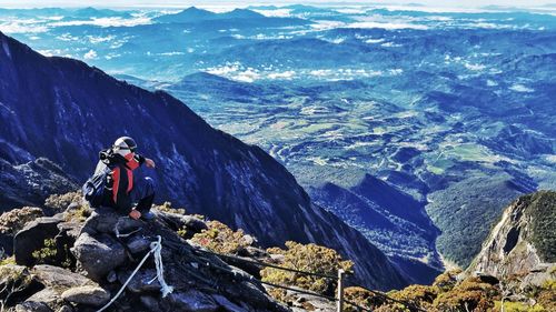 Man sitting on rock against mountains