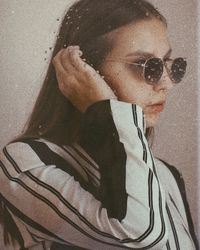 Close-up portrait of young man wearing sunglasses against wall