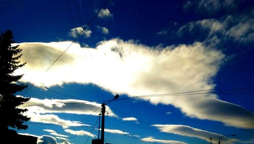 Low angle view of electricity pylon against blue sky