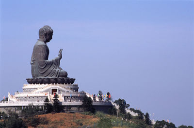 Buddha statue on hill at po lin monastery against clear sky